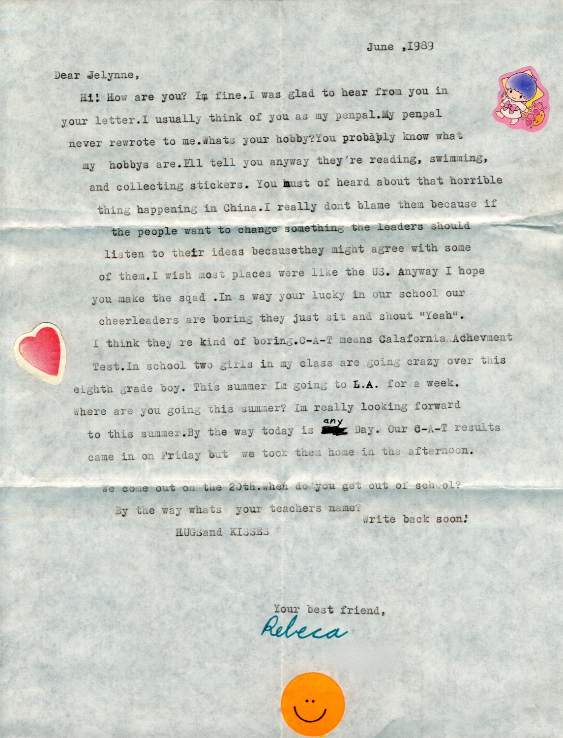 A typed pen-pal letter from June 1989 that begins Dear Jelynne and is signed Rebeca, decorated with a heart sticker, a flower sticker and an orange smiley face.